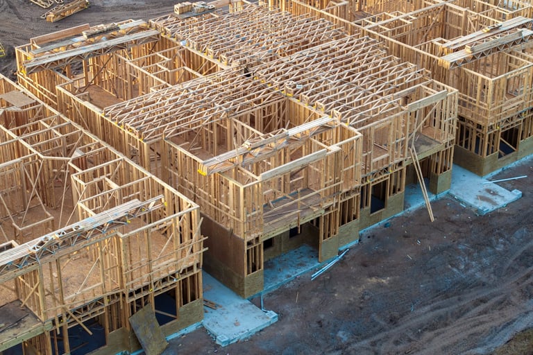 Development of residential housing in American suburbs. Unfinished frames of apartment condos with wooden roof beams under construction. Real estate market in the USA.
