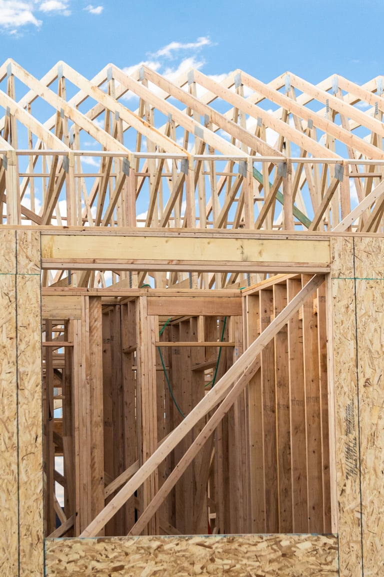 An ongoing construction site in the suburbs, featuring the framing stage of a single-family house.