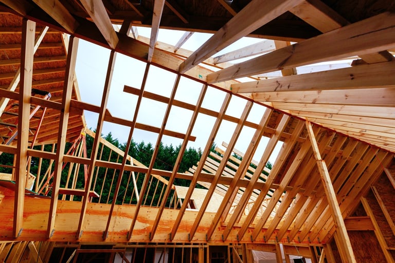 Workers are building wooden house frame, trusses roof supports studs joist overhead.